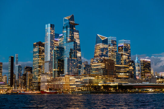 Illuminated Hudson Yards district and The Edge at night. View of New York City west side skyline featuring modern architecture of Hudson Yards and dark water.