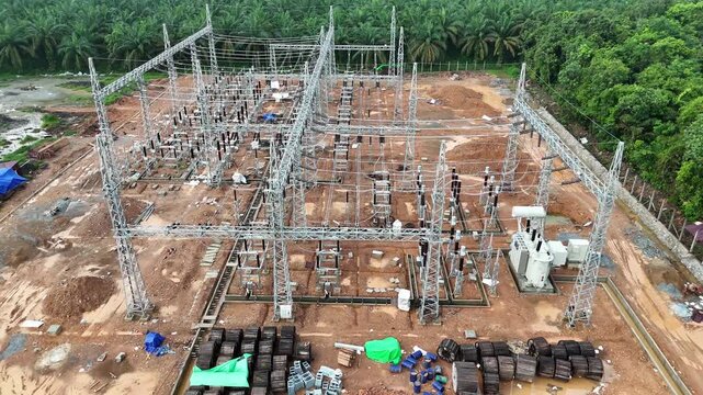 Aerial view showing the construction of a power substation and transformers near a palm oil plantation.