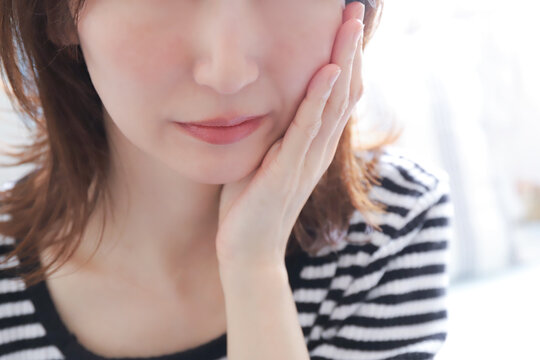 頬を押さえて歯の痛みに耐える女性