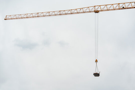 Close-up of a tower crane's horizontal jib and hook block lifting equipment. Concept of urban development, engineering, and heavy machinery.