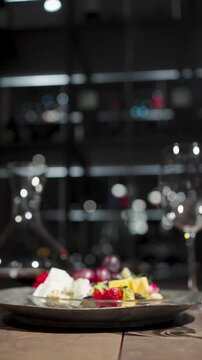 Elegant Wine and Cheese Plate Setting in Luxury Restaurant. Gourmet cheese platter with grapes and strawberries, empty wine glasses, a decanter of red wine, and breadsticks