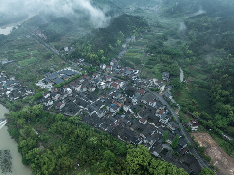 Aerial view of a traditional mountain village shrouded in mist with terraced fields and winding rivers
