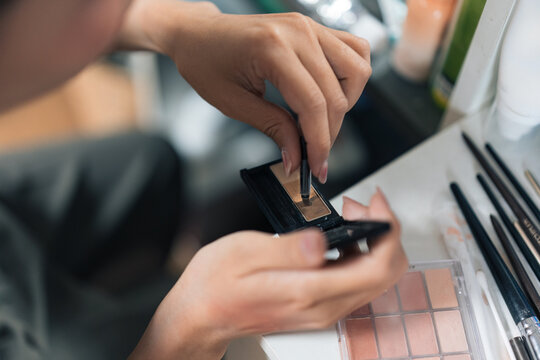 Person using eyebrow kit with cosmetic tools at home