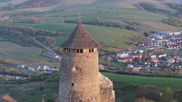 Medieval Stara Lubovna castle tower standing on a hill overlooking the town and surrounding valley illuminated by the warm light of sunset