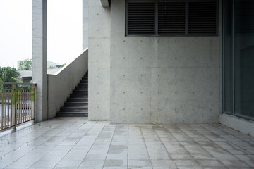 Naklejka premium Concrete building exterior corridor with staircase and ventilation grille under overcast sky
