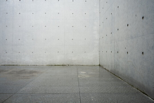 A minimalist space composed of concrete walls and tiled flooring with geometric lines and industrial texture