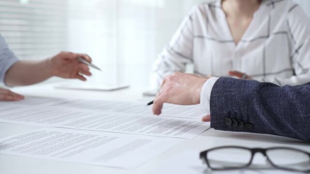 Business people discussing contract details during an important corporate meeting, partners reviewing legal documents with an attorney, collaborating on an agreement