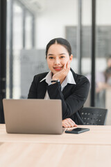 Fototapeta premium Business woman using a laptop computer while working in a bright modern office environment