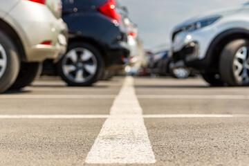 Low angle view of parking lot with white arrow marking on asphalt between parked cars © Dmitrii