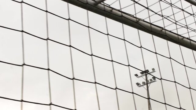 A soccer field net with a view of a floodlight tower inside a stadium during the day in Neiva, Huila, Colombia. Concept of sports