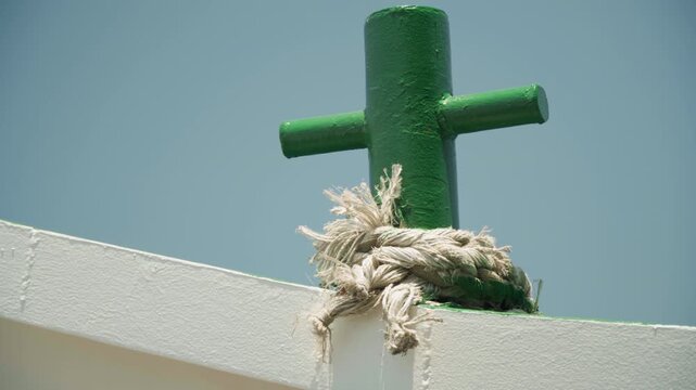 Green bollard frayed rope on bow weathered green metal cleat wrapped with sunbleached frayed rope against clear blue sky, textured paint and saltsprayed edges evoke calm nautical atmosphere, suitable