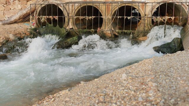 Polluted water and wastewater discharge flows from several large concrete culverts, highlighting issues of urban runoff and environmental contamination.
