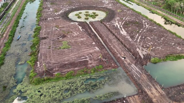 Aerial View of Cleared Construction Site With Canals and Muddy Access Road.