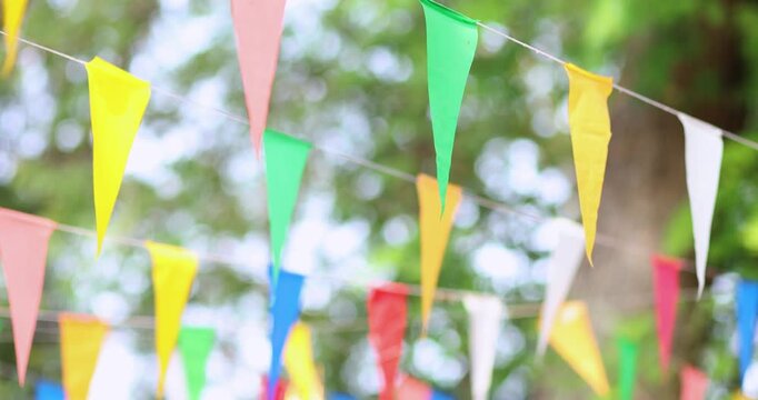 Colorful pennant flags hanging outdoors, gently swaying to create a festive, cheerful atmosphere. Perfect for celebrations, parties, and outdoor events