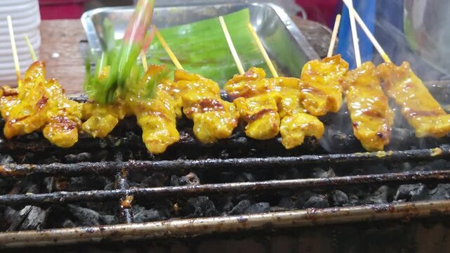 Chef Brushing Glaze on Pork Satay Skewers Grilling over Charcoal