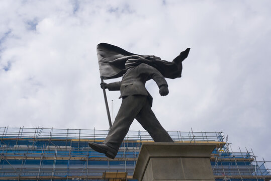Banksy artwork statue in Waterloo Place in London of a man holding a flag that is covering his face. 