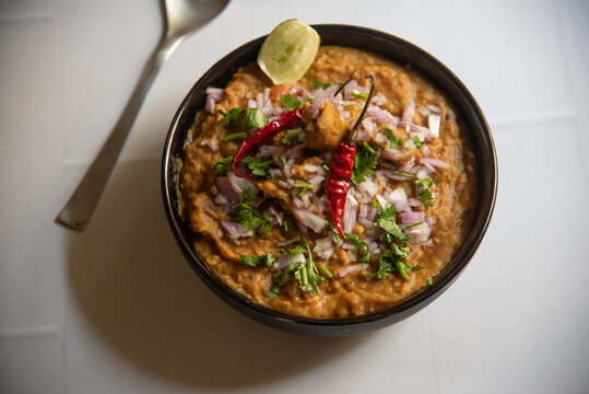 Chicken haleem or halim served with herbs in a bowl. Top view, selective focus. 