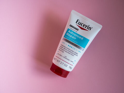 Riga, Latvia - 05.02.2026: Minimalist product shot of Eucerin Advanced Repair Hand Cream in a white tube with a red cap, placed on a soft pink background