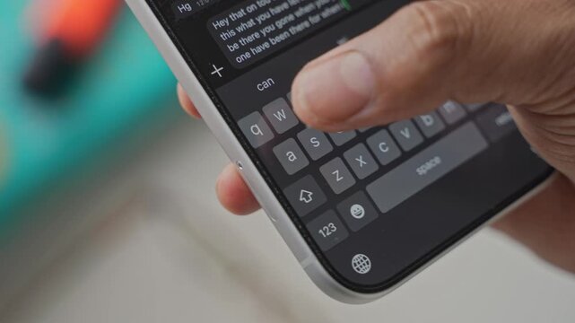 Close-up macro shot of anonymous male hands typing and chatting on a smartphone, fingers tapping a touchscreen keyboard while sending text messages in a modern digital environment. Unrecognizable pers