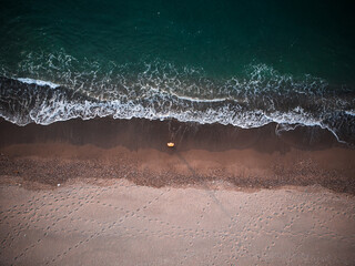 Lonely man relaxing on the beautiful beach at sunset. Sun reflected on beach, Lonely man stands on the beach looks towards the sun light. A man meets the sunset on beach, silhouette of person walking. © Mediterranean sea