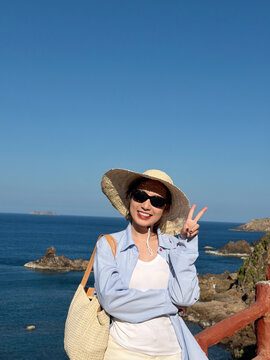 Young woman poses on a coastal path near the ocean during a sunny day