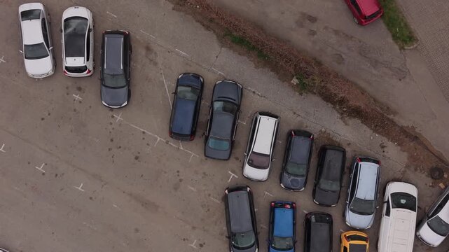Top down aerial view of various cars parked in a public outdoor parking lot