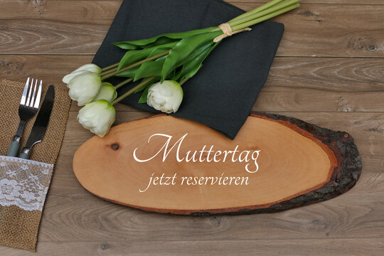 Muttertag jetz reservieren. Tischreservierung auf rustikaler Baumscheibe mit wei&szlig;en Tulpen.