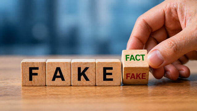 Hand replacing fake with fact on wooden blocks on a table