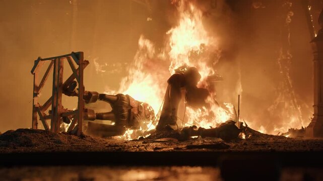 Slow motion. Fallen falla sculptures and wooden framework glow and burn on the ground during La Crema in Valencia, orange light intense