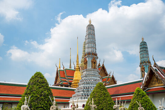 Stunning view of the golden stupa and intricate Prang towers at Wat Phra Kaew within the Grand Palace complex in Bangkok, Thailand, under a bright blue sky.