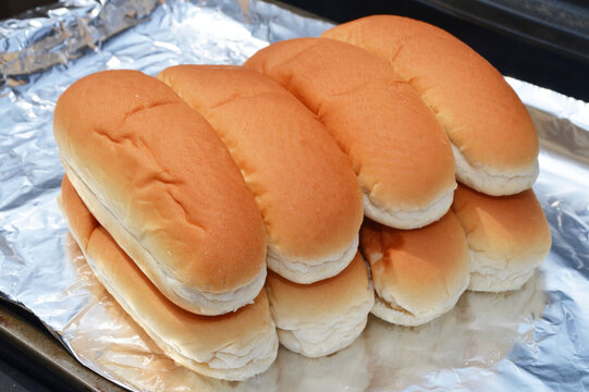 Hotdog buns warming on a grill on foil, closeup.