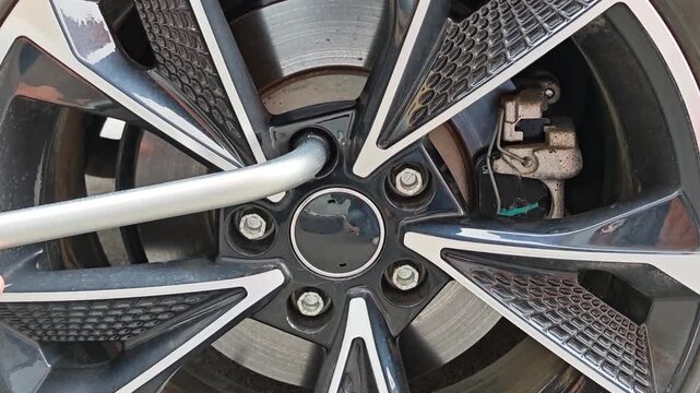 Close up of hands tightening lug nuts on an alloy wheel. car wheel assembly, detailed auto repair work.