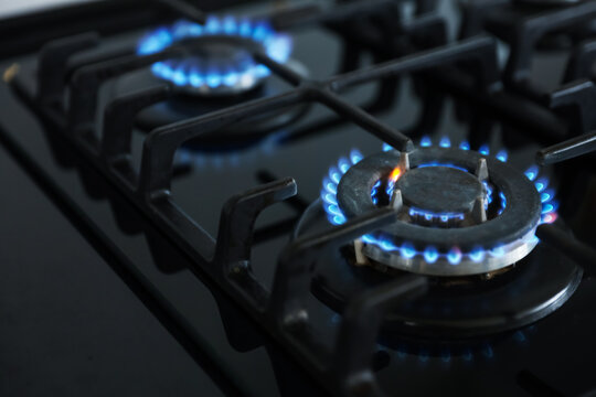 Gas burners with blue flames on stove, closeup. Space for text