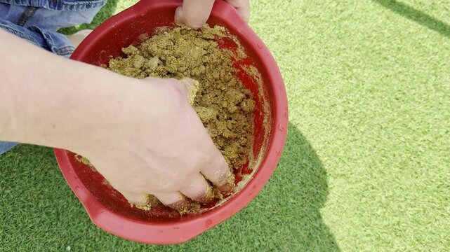 Close up of hand picking worms from bowl with fishing bait mixture, preparing ground bait for fishing, outdoor activity, angling and fishing setup concept