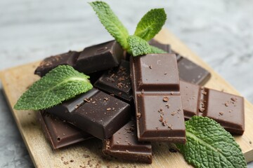 Pieces of yummy chocolate and mint leaves on grey table, closeup © New Africa
