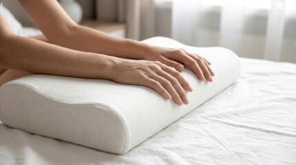 Fototapeta premium A person places their hands on a soft pillow resting on a bed. The room is bright with sunlight coming through the window. The setting suggests comfort and relaxation during the day