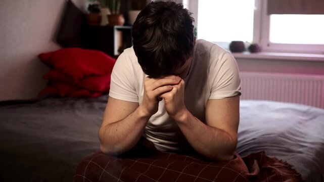 Man with hangover waking up sitting in bed feeling terrible headache