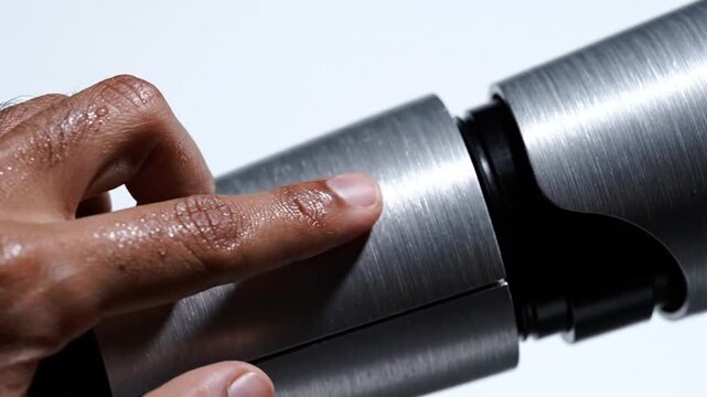 Hand holding metal pipe fitting.