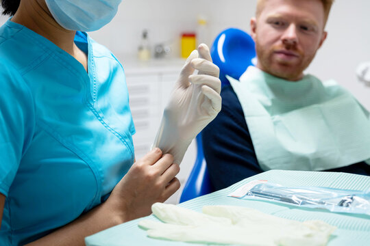 Dentist putting on sterile medical gloves before a dental checkup with a patient
