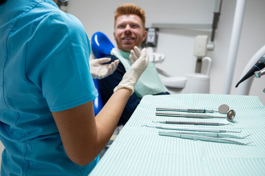 Dentist explaining dental check up or treatment to a male patient in a modern clinic