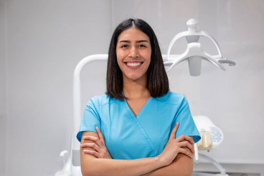 Young woman dentist smiling and standing with crossed arms in a dental clinic