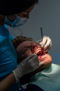 Dentist performing a routine dental checkup on a male patient in a clinic