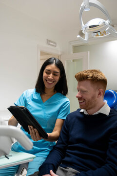 Dental professional explaining treatment options to smiling patient in modern dental clinic