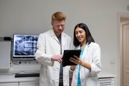 Dental professionals analyzing X ray and medical information on a tablet in a modern clinic