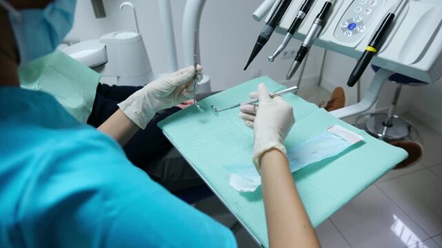 Dentist in a clinic is preparing sterile tools before a dental examination on a male patient
