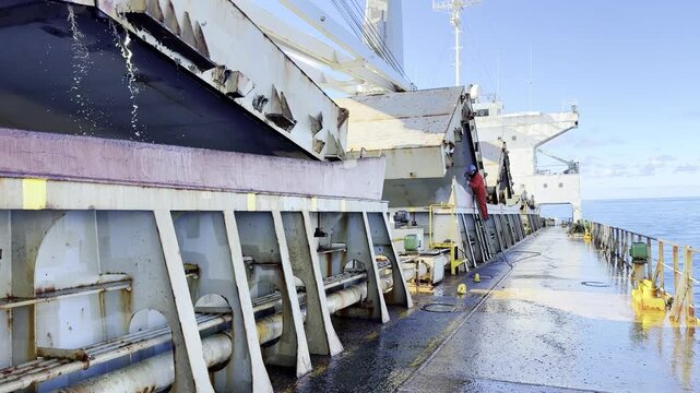 ship crew, able seaman, seafarer use high pressure water blaster for remove rust from the coamings of ship's cargo holds. maritime job and seafarers life.