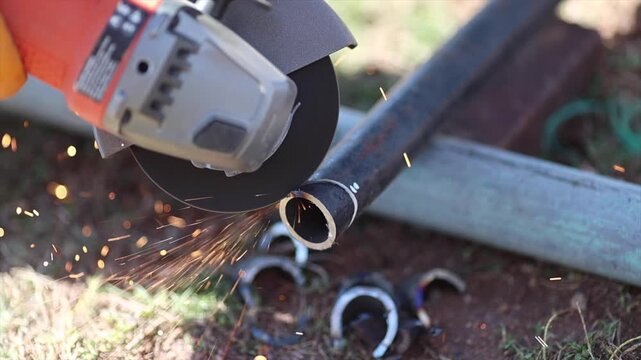 Man is cutting a metal list by angle grinder saw.