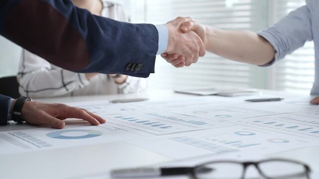 Business executives shaking hands, sealing an agreement after successful negotiations in a bright office, symbolizing partnership, collaboration, and a mutually beneficial deal signing