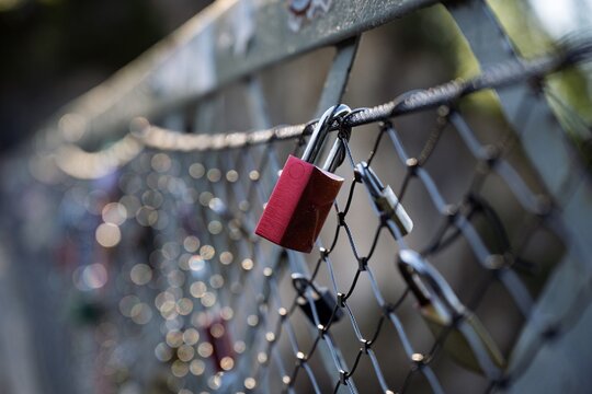 Close up of a red love lock on the Marienbruecke bridge in Schwangau with blurred bokeh background and more padlocks