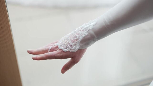 Close-up of a bride putting on delicate white lace gloves as part of her wedding attire